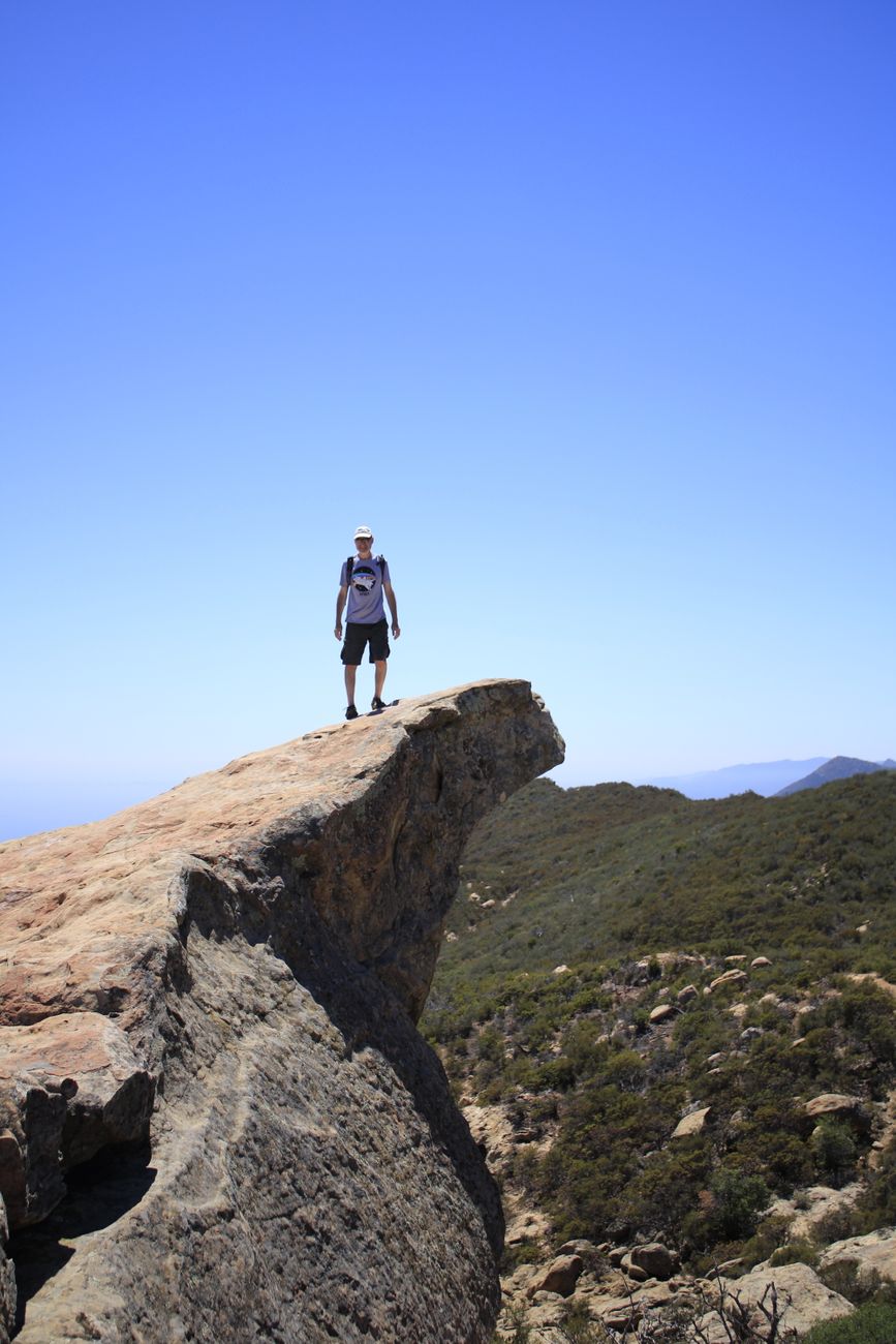 person sitting on mountain cliff